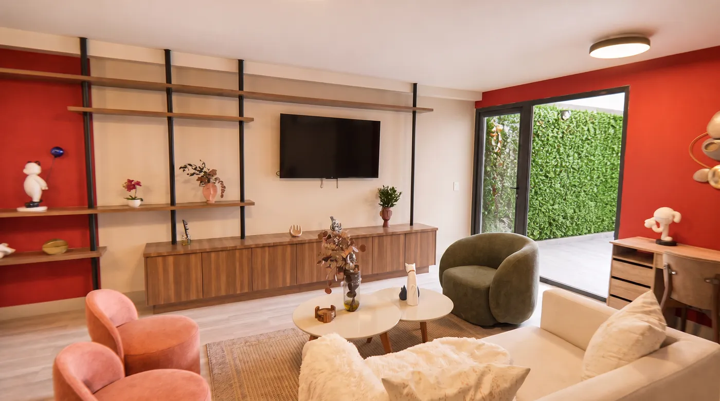 Sala con pared roja, estantería y ventanal al jardín