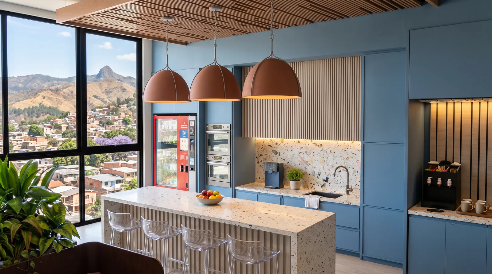 Cocina comunal con isla de terrazo, hornos y barra de café